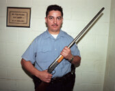 Special operations officer displays firearm confiscated from gang members in housing project, Chicago, Illinois, 2000